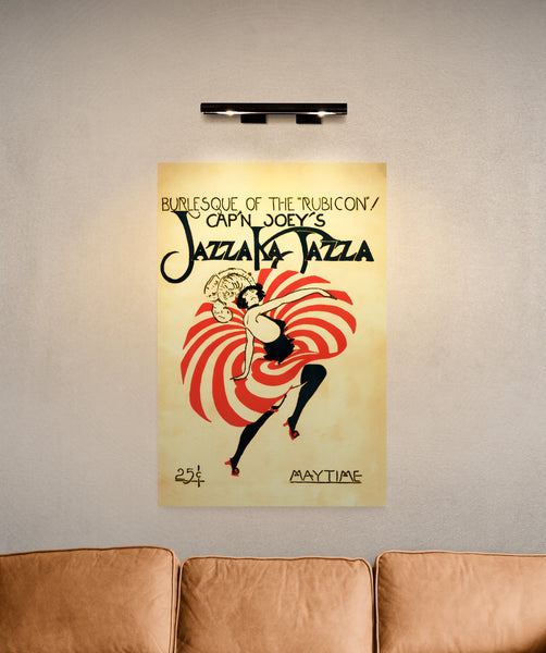 A large matte poster of a cover of "Jazza Ka Jazza" - a 1922 Jazz magazine. Features a stylized burlesque dancer with a vivid, red skirt. The dancer is in motion, twirling her skirt. Hung above a couch; illuminated by a picture light.
