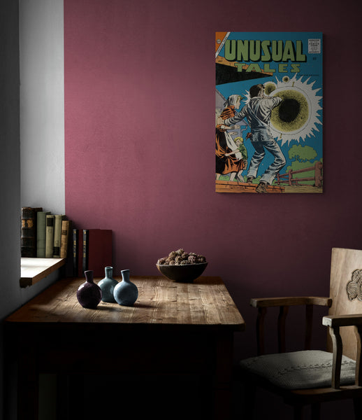 A large matte paper poster of the cover of the 1958 comic book "Unusual Tales #12" hung next to a window in a dimly lit den above an old wooden table
