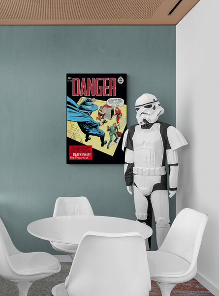 A large matte paper poster of the cover of the 1964 comic book "Danger #12" hung on a dusty teal wall next to a propped up Star Wars Stormtrooper costume